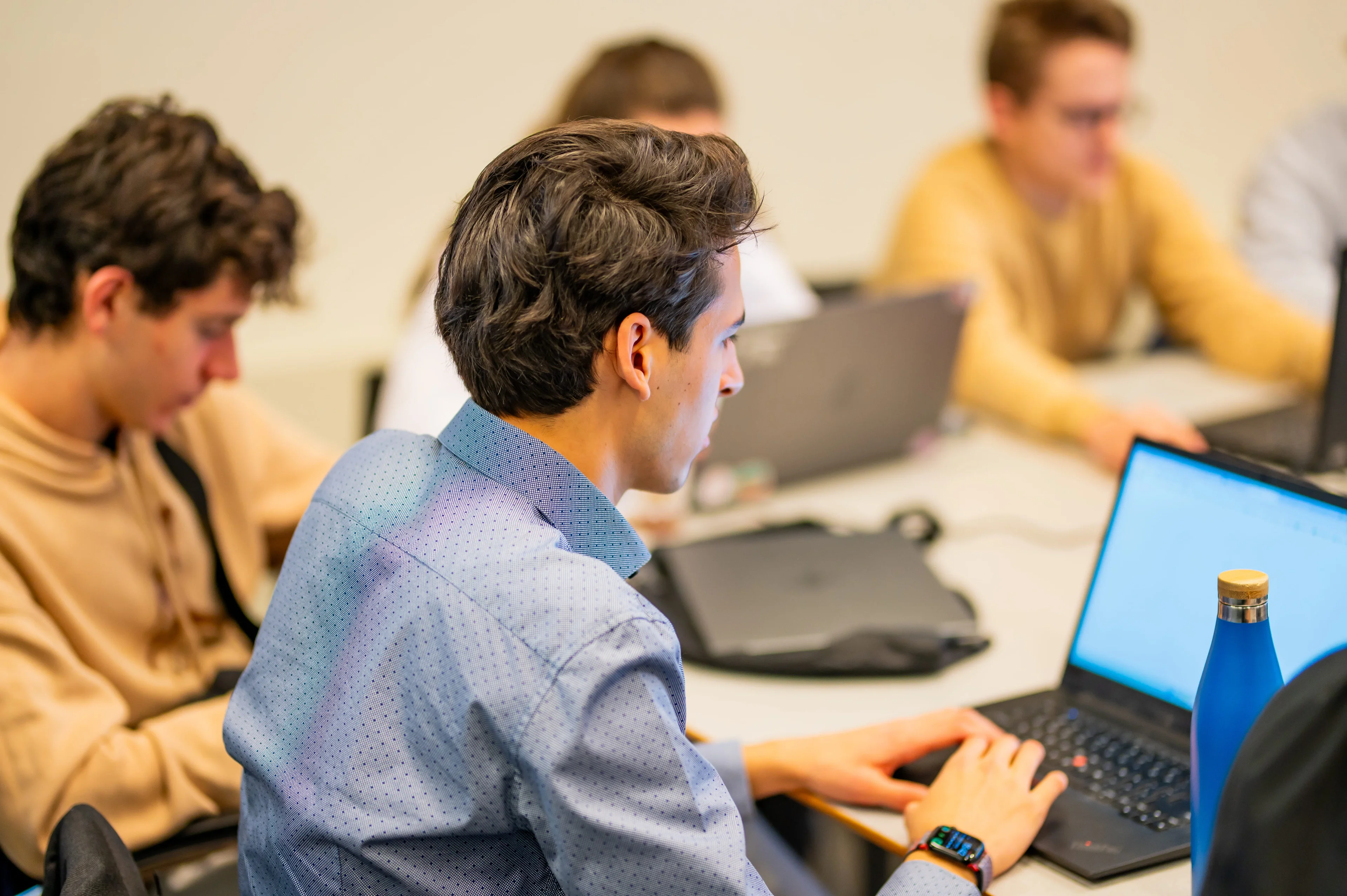 Deelnemers werken geconcentreerd achter hun laptops tijdens een workshop